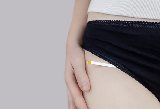 Bacterial Vaginosis. Vaginal pH. Girl shows sticks for measuring acid-base balance of genital organs. Self-diagnosis. Normal acidity level shown in colors and must be compared with the standard