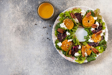 Christmas appetizer. Christmas wreath salad with beetroot, tangerines, feta cheese and pecans on the festive table. View from above. Copy space.