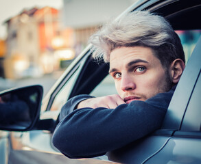 A man leaning his head out of a car window. Photo of a man leaning out of a car window, looking at...
