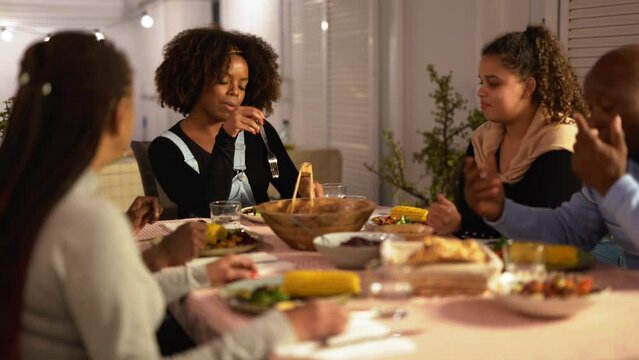 Happy african family eating dinner together at home on patio - Party, bonding and holiday concept