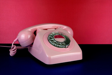 Vintage Pink Telephone on a Blue Surface with Red Background