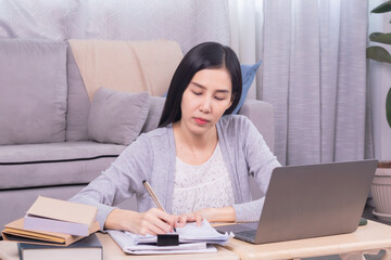 Asian happy female working at home calculate bookkeeping for tax declarations using modern technology laptop, well-organized planning financial payment for housing loan, women working paperwork bills