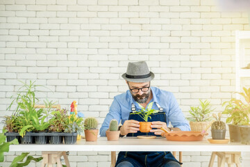 A senior man or grandfather with a mustache enjoys gardening for the tree at home after retirement
