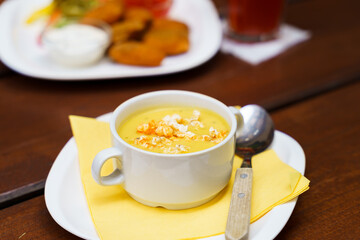 Bowl of sweet corn soup with popcorn on a wooden table