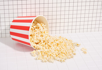 Appetizing salty popcorn scattered out of a bucket. Cinema time and entertainment.