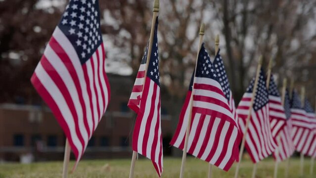Close up of Slow waving many American flags blowing in the wind on a cloudy day. Patriotic concept for US holidays, 4th of July, Memorial day or Veteran's day. Close up shot