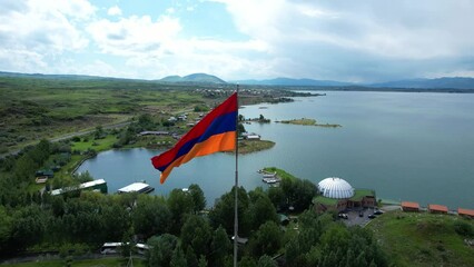 Aerial view Armenian flag. Drone fly around Armenian flag with water background. Flag near lake. 