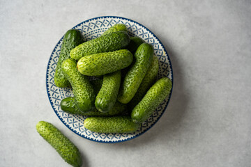 Fresh cucumbers on a plate, light gray stone background, top view, space for text