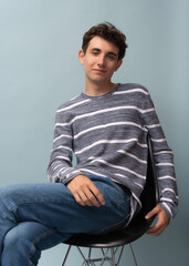 portrait of a young man in a light gray striped pullover posing for the camera, different emotions, on a light background
