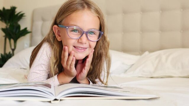 surprise excited toddler in glasses reading interesting encyclopedia new facts information. looks at camera, opens eyes and mouth Developing smart children. fantasy for kids. Kid emotion