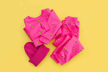 Pink jumper and pant with hat. Set of children's clothes and accessories for spring or autumn on  yellow background. Fashion kids outfit. Flat lay, top view
