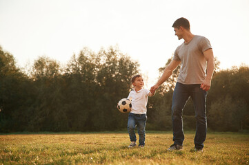 Soccer ball in hands. Father and little son are playing and having fun outdoors