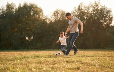 Activity, running and playing soccer. Father and little son are playing and having fun outdoors