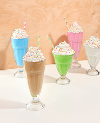 Holiday sweet composition with colored milkshakes in glasses. Whipped fresh cream with colored sprinkles. Birthday party.