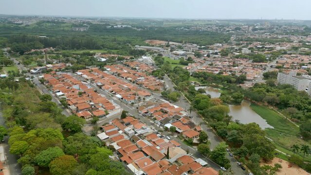 Vista a&eacute;rea de bairro residencial na cidade de Paul&iacute;nia com casas de telhado laranja e muitas &aacute;rvores e vegeta&ccedil;&atilde;o ao redor. Brasil, 2023.