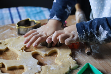 Kid hand holding fancy cutter cookie on a pastry cookie dough.mess wooden board with flour, rolling...