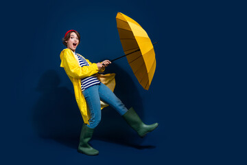 Full body photo of funny overjoyed joking positive girl open her bright yellow umbrella fall season rain isolated on blue color background