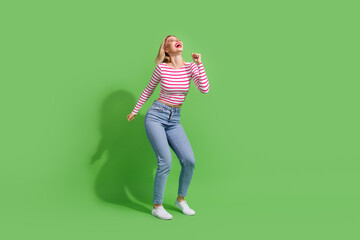 Full length photo of cheerful pretty girl dressed striped shirt having fun dancing discotheque empty space isolated green color background