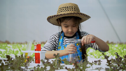 Cheerful of asian girl science experiment in chemical at vegetables organic hydroponic farm. child playing test tube to agricultural engineer studying chemistry in organic farming. dream kid farmer - obrazy, fototapety, plakaty
