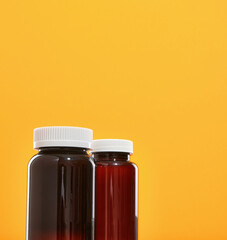 Two brown medical jars with white lids with drugs and supplements are on the table. Copy space for text.