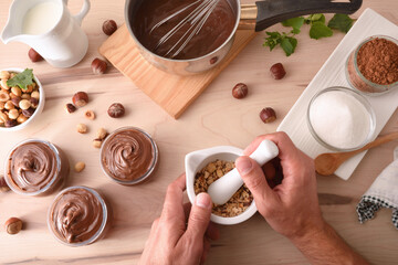 Grinding hazelnuts in mortar to make hazelnut cream with chocolate