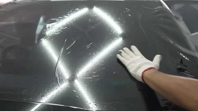 Automotive technicians make car windows in preparation for installing car window tint film.