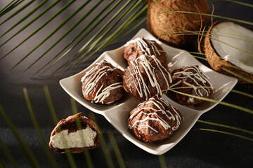 Chocolate profiteroles, eclairs, with coconut cream on a dark background
