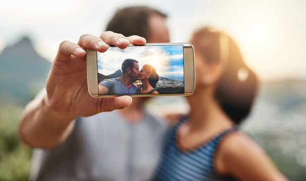 Phone screen, selfie and couple kiss in nature outdoor on summer vacation together. Smartphone, romance and picture of man and woman in countryside for connection, memory of love and relationship