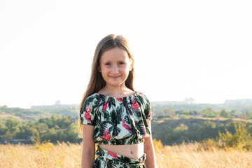 Portrait of a happy five-year-old girl in nature walking in the field in the summer.