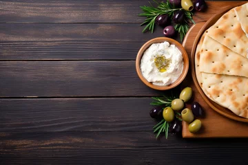 Fotobehang Alluring flat lay of Greek cuisine essentials, harmonizing olives, feta, and pita bread, neatly arranged, leaving generous empty space for your unique content. © Kristian
