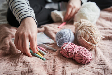 Cropped view of the young woman knitting at the bed during the weekends - obrazy, fototapety, plakaty