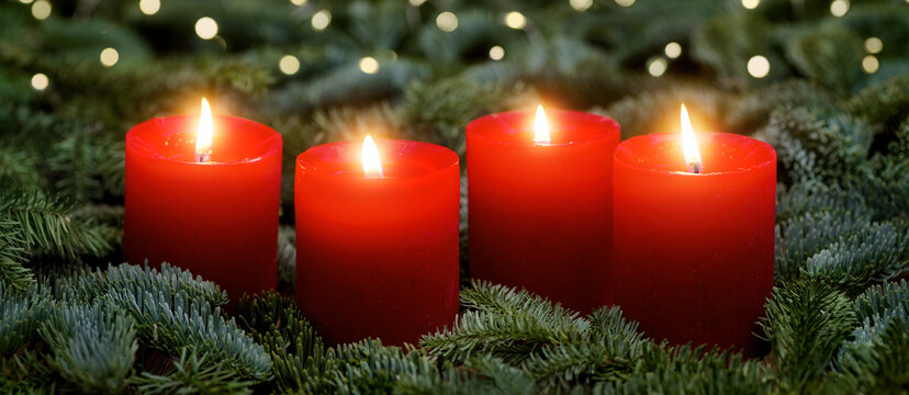Red Advent candles, all four burning, with fir branches and bokeh lights. The image is part of a set.