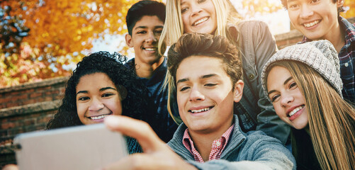Smile, friends and a selfie in nature for bonding, fun and video call in autumn. Happy, together and diversity of kids taking a photo on technology in a park for social media or live streaming