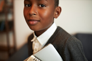 Closeup cropped image of black teen schoolboy on his way for class at school, standing on blurred...