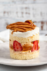 Strawberry and caramel cake. Fresh cake with caramel and strawberries on a plate. Close up