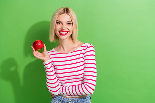 Photo of optimistic pleasant woman with bob hairstyle wear striped shirt hold ripe apple in hand isolated on green color background