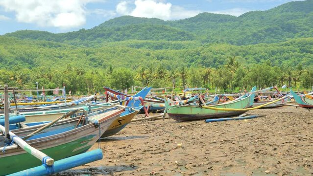Wooden fishing boats are densely parked in a dry and dirty harbor at noon on the coast of Java, Indonesia. Depicts the difficulty of traditional fishermen getting fish and losing their jobs.