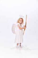 Little beautiful girl, child in image of cupid, angel holding bow isolated over white studio background. Valentines' day. Concept of childhood, imagination, fantasy, fashion and beauty, holidays