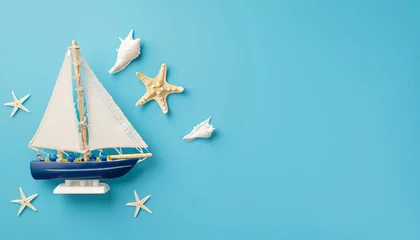 Tuinposter Top view of ship, sailboat toy with starfishes on blue background with copy space © Loliruri