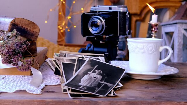 candle burning, old family photos in vintage interior, stack nostalgic pictures, vintage photographs 50s, 40s, retro accordion camera on wooden table, concept genealogy, memory ancestors, family tree