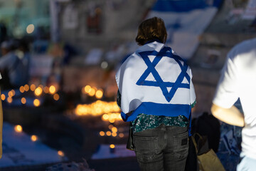 Lisbon, Portugal October 10, 2023. A woman at the memorial to the fallen Israelis in October 2023 at dusk, , with the flag of Israel on her shoulders