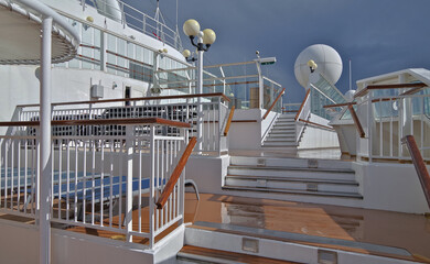 Outdoor promenade and pool decks of modern cruiseship cruise ship liner with sun loungers and deck...