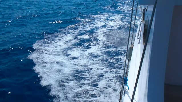 Wooden yacht in foaming white sea. A nice wooden white yacht deck floating and foaming the sea in the sun light during summer traveling.