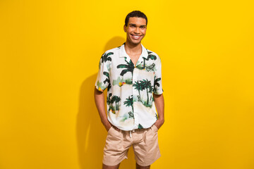 Fototapeta premium Portrait of pleasant cheerful nice guy wear print clothes with ring in nose hold hands in pockets isolated on yellow color background