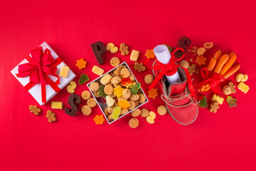 Sinterklaas, Saint Nicholas day background. Little kid red shoe with carrots and sweets, trooigoed, pepernoten, candy. Dutch Christmas holiday greeting card 