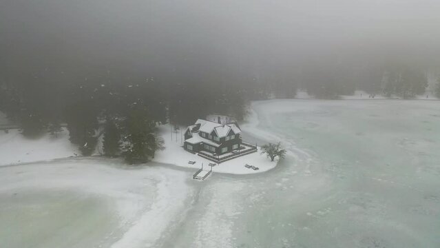 A frozen lake and a beautiful house under the snow in winter in Bolu Golcuk Nature Park. Bolu Gölcük Nature Park, Turkey.