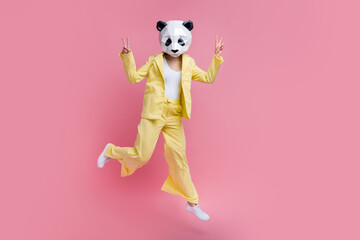 Full size photo of weird excited 3d panda mask girl jump show v-sign empty space isolated on pink color background © deagreez