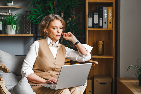 Stress, anxiety, problems. Tired thinking confident mature middle aged elderly businesswoman working with laptop in modern office workplace chair. General manager,ceo. Business woman in suit sitting