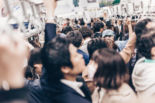 Passengers traveling by Tokyo metro. Business people commuting to work by public transport in rush hour. Shallow depth of field photo. Horizontal composition.