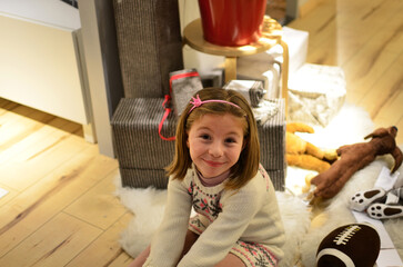 Little girl sitting on the floor in front of a fireplace with gifts